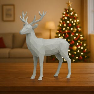 May include: A geometric, light gray deer figurine with detailed antlers stands on a wooden surface. The deer is in front of a Christmas tree decorated with lights and ornaments, creating a festive holiday scene. The figurine is a modern, minimalist decoration.