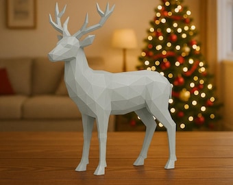 May include: A geometric, light gray deer figurine with detailed antlers stands on a wooden surface. The deer is in front of a Christmas tree decorated with lights and ornaments, creating a festive holiday scene. The figurine is a modern, minimalist decoration.