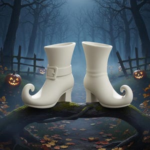 Può includere: Un paio di stivali da strega bianchi con punte arricciate e una fibbia. Gli stivali sono ambientati su uno sfondo di foresta spettrale con lanterne di zucca, creando un tema di Halloween.