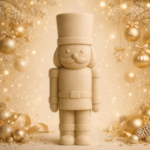 May include: A beige-colored nutcracker figurine with a tall hat, mustache, and a belt. The festive decoration is surrounded by gold Christmas ornaments, pinecones, and ribbons, creating a warm holiday scene.