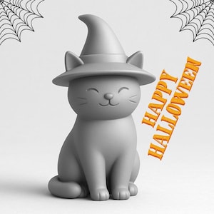 May include: A gray cat figurine wearing a witch hat, with the text "HAPPY HALLOWEEN" in orange. The cat is sitting with a smiling face. Two spiderwebs are in the background. A Halloween-themed decoration.