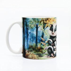 May include: White ceramic mug with a colorful illustration of a family of badgers in a forest setting. The badgers are black and white with brown noses and eyes. The forest is painted in shades of blue, green, and yellow.