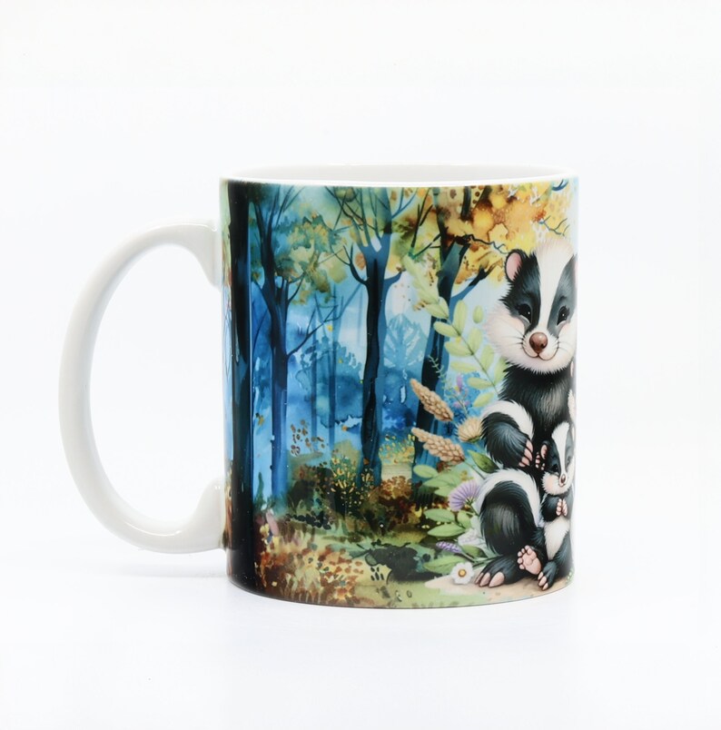 May include: White ceramic mug with a colorful illustration of a family of badgers in a forest setting. The badgers are black and white with brown noses and eyes. The forest is painted in shades of blue, green, and yellow.