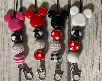May include: Four colorful Mickey Mouse themed lanyards with black and white patterned beads and a silver clip. The lanyards are pink, red, black, and white.