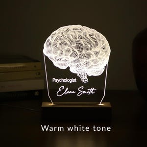 Personalized 3D illusion lamp featuring a detailed brain anatomy design, illuminated in a white tone,  perfect as a unique gift for mental health professionals.