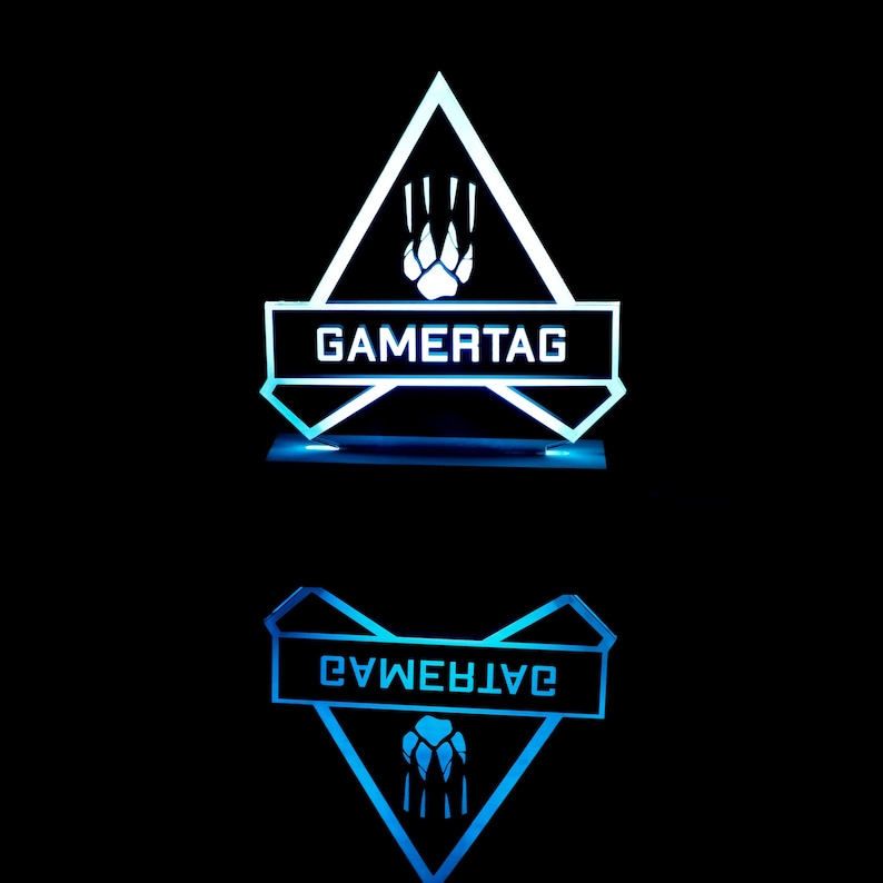 May include: A white and blue illuminated acrylic plaque with a triangle shape and a paw print design. The plaque has the text "GAMERTAG" on it.