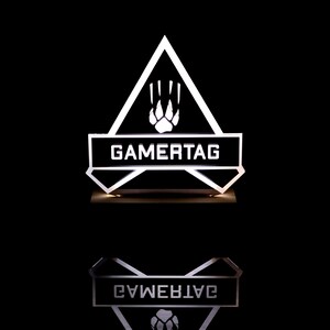 May include: A white illuminated sign with a black triangle shape. The triangle has a paw print inside and the text "GAMERTAG" on a black rectangle at the bottom.