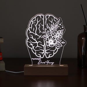Personalized 3D illusion lamp featuring a floral brain anatomy design, illuminated in a white tone,  perfect as a unique gift for mental health professionals.