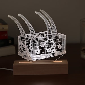 Può includere: Una lampada bianca stampata in 3D a forma di organo umano con una base in legno. La lampada è accesa ed emana una luce calda.