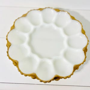 May include: White milk glass egg plate with a gold rim. The plate has eight individual sections for holding eggs.