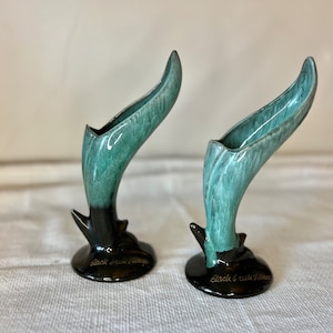 May include: Pair of vintage green and black ceramic bud vases with a unique curved design. The vases are marked "Black & White Village".