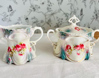 Juego de cremera y azucarero de porcelana vintage pintado a mano, con rosas rosas y detalles dorados.