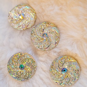 May include: Four iridescent gold-toned buttons with a swirling design and a clear rhinestone in the center.