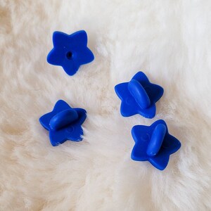 May include: Four blue star-shaped pin backings. The pin backings are made of plastic and have a small hole in the center.