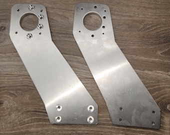 May include: Two silver metal brackets with multiple holes and a larger circular hole in the center. The brackets are angled and have a smooth, polished finish.
