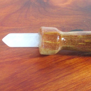 May include: A wooden tool with a white, pointed tip. The handle is brown with yellow accents and a glossy finish. The tool is designed for a specific purpose, likely related to woodworking or crafts.