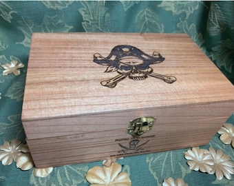 Puede incluir: Una caja de madera con temática pirata. La tapa presenta un diseño de calavera y huesos cruzados con un sombrero de pirata. La caja tiene un cierre metálico y el texto "Pirates To Be Master" y un diseño de calavera y huesos cruzados en la parte delantera.