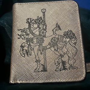 Cartera compacta para mujer en piel dorada grabada con el escudo del caballo del carrusel