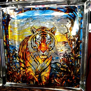Op de afbeelding: Een gekleurd glasblok met een tijger die door een junglescène loopt. De tijger is oranje, zwart en wit met een gedetailleerd ontwerp. De achtergrond is in levendige kleuren: blauw, groen en geel.