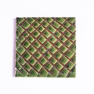 Könnte beinhalten: Eine grüne Keramikfliese mit einem Rautenmuster in brauner Glasur.