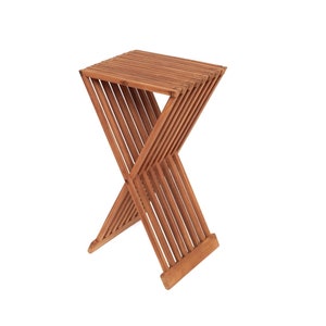 Könnte beinhalten: Ein klappbarer Holzhocker mit naturbrauner Oberfläche. Der Hocker besteht aus mehreren Holzlatten, die ineinandergreifen, um ein stabiles und kompaktes Design zu schaffen.