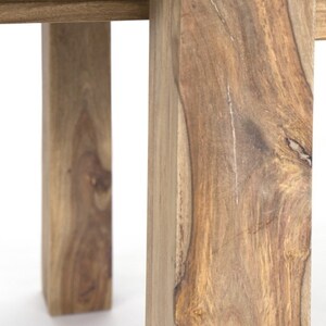 May include: Close-up of a wooden table leg, showcasing the natural grain and texture of the wood. The leg is a warm brown color, with visible knots and variations in the wood grain. The table appears to be sturdy and well-crafted.