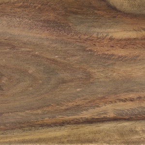 May include: Close-up of a wooden surface with a natural wood grain pattern. The wood has a warm, brown color with darker streaks and knots, creating a textured appearance. The grain flows horizontally across the frame.