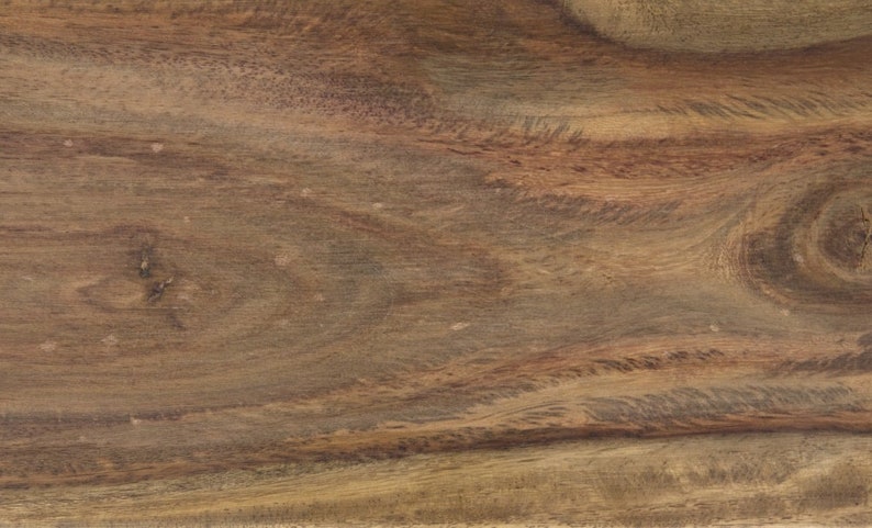May include: Close-up of a wooden surface with a natural wood grain pattern. The wood has a warm, brown color with darker streaks and knots, creating a textured appearance. The grain flows horizontally across the frame.