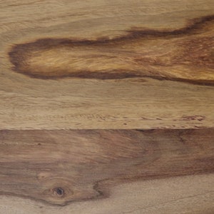 May include: Close-up of a wooden surface with a natural wood grain pattern. The wood features varying shades of brown and tan, with darker, swirling patterns. The texture appears smooth, highlighting the natural beauty of the wood.