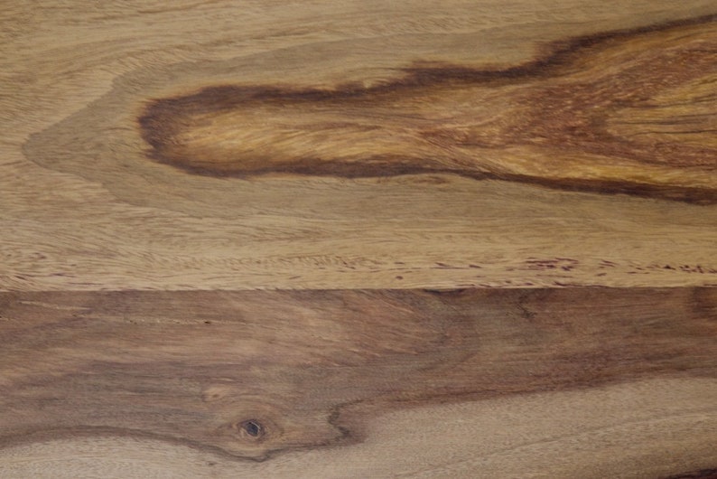 May include: Close-up of a wooden surface with a natural wood grain pattern. The wood features varying shades of brown and tan, with darker, swirling patterns. The texture appears smooth, highlighting the natural beauty of the wood.