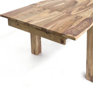 May include: A light brown wooden dining table with a rectangular top and four square legs. The table has a natural wood grain pattern and a simple, modern design. The table's dimensions are not visible in the image.