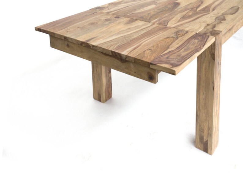 May include: A light brown wooden dining table with a rectangular top and four square legs. The table has a natural wood grain pattern and a simple, modern design. The table's dimensions are not visible in the image.