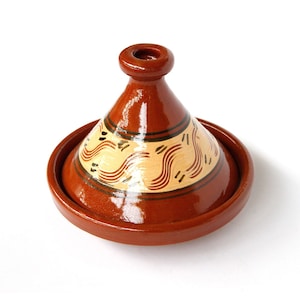 Könnte beinhalten: Eine braune Keramik-Tagine mit Deckel, die mit einem dekorativen Muster aus wellenförmigen Linien in Braun und Creme auf dem Deckel verziert ist. Die Tagine ist ein traditioneller marokkanischer Kochtopf.