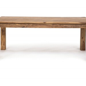 May include: A rectangular wooden dining table with a natural finish. The table has a solid, blocky design with four sturdy legs. The wood grain is visible, showcasing the natural color variations. This table is approximately 72 inches long and 36 inches wide.