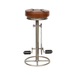 Könnte beinhalten: Ein brauner Leder-Barhocker mit einem Metallgestell und Fußpedalen. Der Hocker hat eine Kette und Zahnräder an der Seite.
