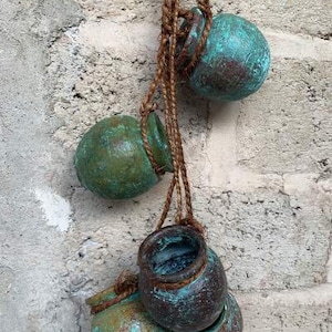 Könnte beinhalten: Vier kleine, tealfarbene Hängetöpfe mit rustikalem, gealtertem Aussehen. Die Töpfe sind mit braunem Bindfaden zusammengebunden.