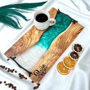 May include: A wooden serving tray with a green and white epoxy resin inlay. The tray has a natural wood finish and features a personalized inscription that reads "Jill Wilson".
