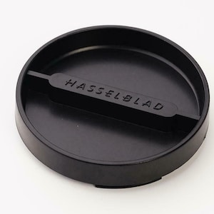 May include: Black camera lens cap with the word "HASSELBLAD" embossed on the top.