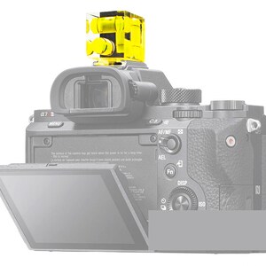 May include: A black digital camera with a bright yellow level attached to the top. The camera has a flip-out screen and various buttons and dials. The level is a clear, cube-shaped device with yellow liquid inside.