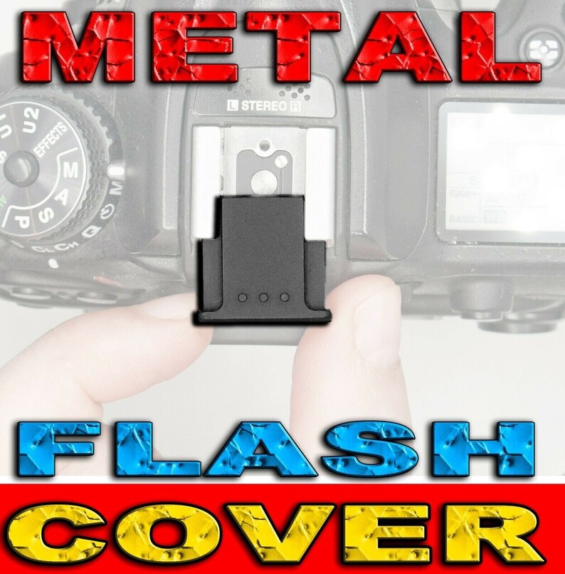 May include: A black metal flash cover for a camera. The cover is rectangular in shape with a small lip on the bottom. The cover is designed to protect the flash from damage.