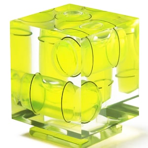 May include: A clear, cube-shaped level with multiple yellow bubble vials. The vials are arranged to indicate levelness on different axes. The level sits on a clear base, showcasing its design and functionality for construction and DIY projects.