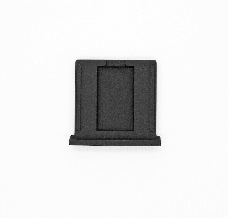 May include: Black plastic camera lens adapter with a rectangular opening.