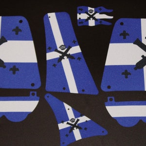 Könnte beinhalten: Ein Set aus sechs blauen und weißen Stoff-Patches mit einem weißen Kreuz und einem schwarzen Kronen- und gekreuzten Kanonen-Design. Die Patches sind zum Nähen oder Kleben auf ein Stoffprojekt gedacht.