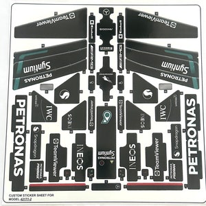 Op de afbeelding: Een stickerblad voor een LEGO-model auto met een zwart-wit ontwerp. Het blad bevat logo's voor Petronas, Ineos, TeamViewer, IWC en Snapdragon. Het blad bevat ook de tekst "Custom Sticker Sheet for Model 42171-2".