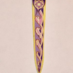 May include: A purple, pink, and yellow fabric bookmark with a floral design.