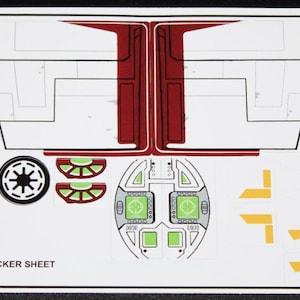 Könnte beinhalten: Ein weißer Aufkleberbogen mit einem benutzerdefinierten Design für ein Raumschiff. Der Bogen enthält Aufkleber für das Cockpit, die Flügel und die Räder des Schiffes. Die Aufkleber sind in Schwarz, Weiß, Rot und Gelb.