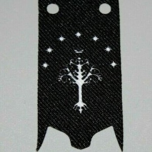 May include: Black fabric patch with a white tree and stars design. The tree has a single trunk and branches with leaves. The text "The One Ring" is not visible in the image.