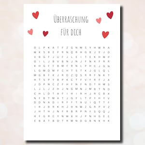 以下が含まれることがあります： 赤いハートのデザインと「Überraschung für dich」というテキストが書かれた白いカード。「Überraschung für dich」は英語で「Surprise for you」という意味です。カードには、黒いアルファベットの文字で構成された単語探しパズルも掲載されています。
