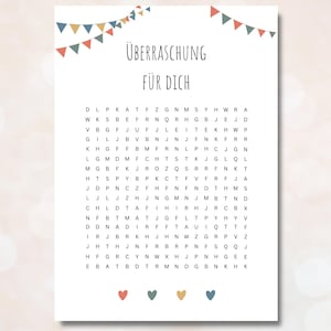 Puede incluir: Un papel blanco con un juego de búsqueda de palabras y el texto alemán "ÜBERRASCHUNG FÜR DICH" en la parte superior. Guirnaldas coloridas decoran la parte superior y corazones en la parte inferior.