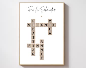 May include: A white framed print with the text "Familie Schneider" at the top. The print features a crossword puzzle made of wooden tiles with the names "Melanie", "Sebastian", "Finn", and "Annie" spelled out.